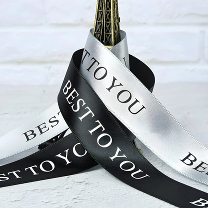 Seven satin ribbon widths laid flat, paired with engraved metal tags for brand consistency.